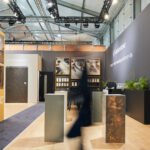 Modern exhibition booth showcasing interior design materials, samples, and promotional displays under bright lighting.