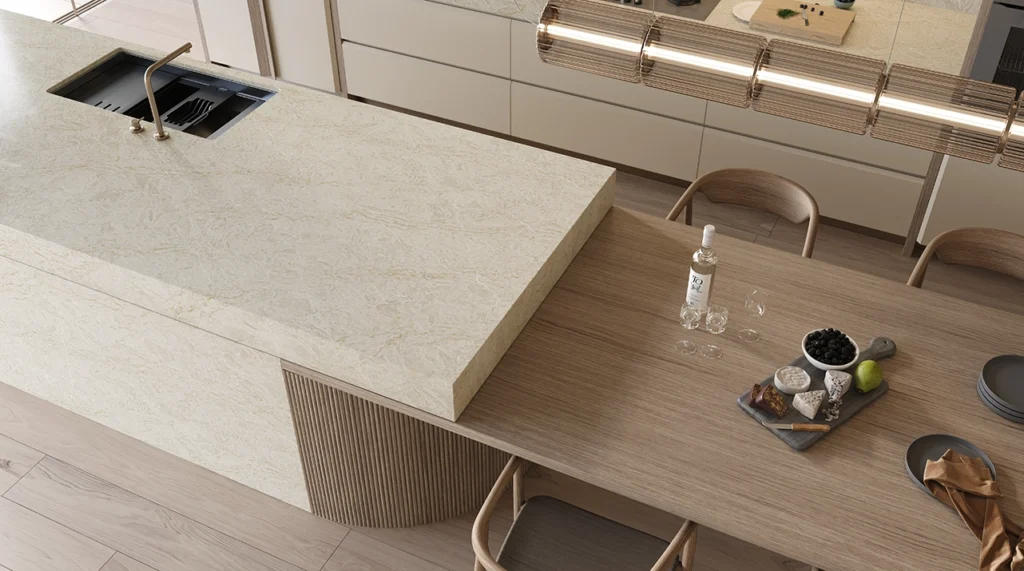 Caesarstone ICON 8251 Taj Whisper Kitchen with modern kitchen with marble island, wood dining table, chairs, fruit bowl, and water bottle.