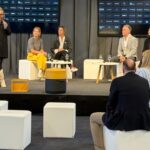 Panel discussion on a stage with audience, large