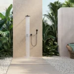 Caesarstone Porcelain 546 Thalassa in Outdoor shower area with plants, stone flooring, wooden vanity, round mirror, and copper sink.